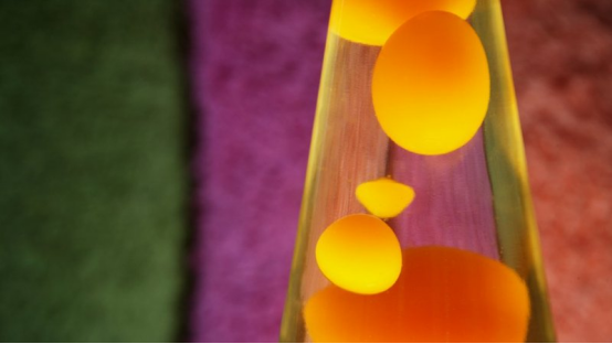 An orange Lava Lamp on Earth, demonstrating how gravity pulls cooled wax downward—a process that would fail in zero gravity.